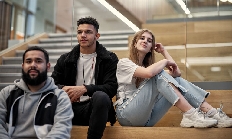 A group of diverse, multicultural students sitting on stairs.