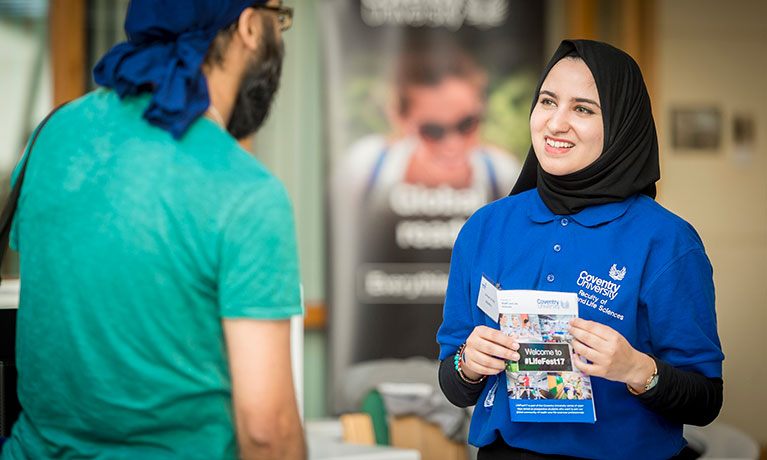 A student support staff member talking to a student