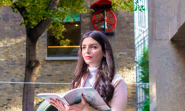Female student sat outside reading a book