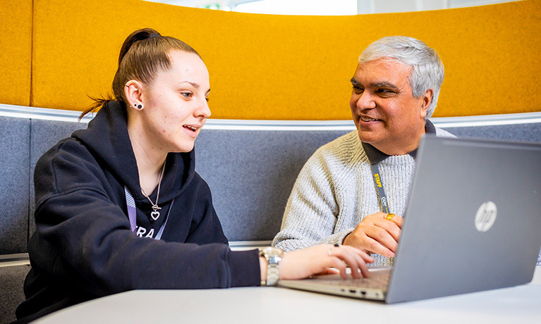 Student and a lecturer sat together working on a laptop
