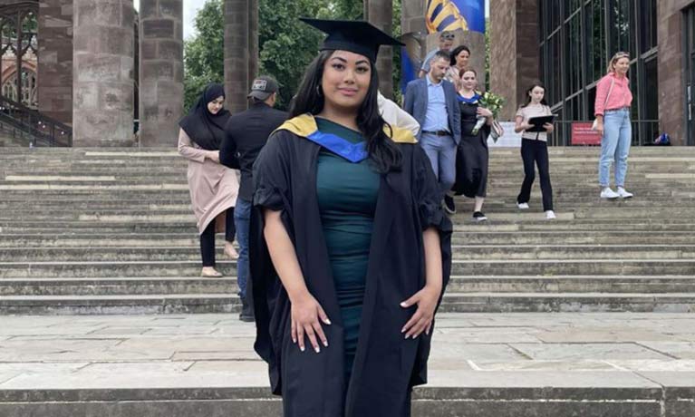 Eunice in her graduation cap and gown outside Coventry Cathedral 