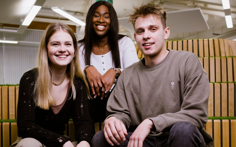 Three students with big smiles, posing happily at Coventry University
