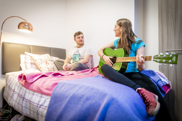 Two students playing guitar on a nice apartment