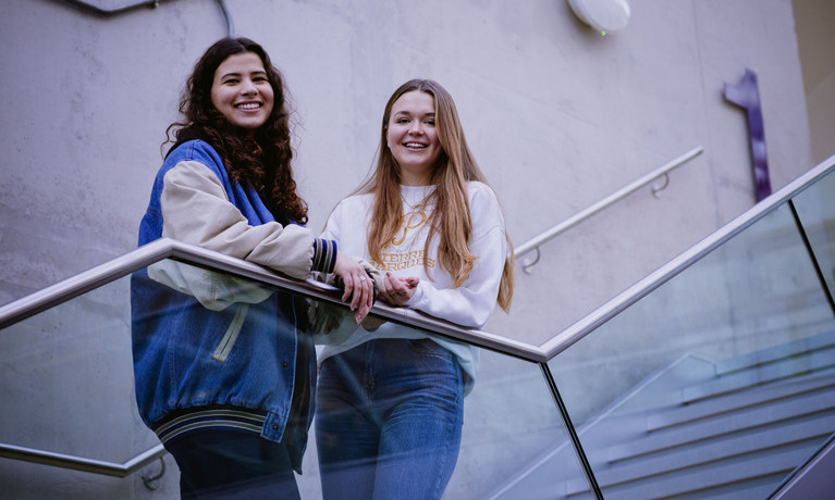two female students standing on a set of stairs