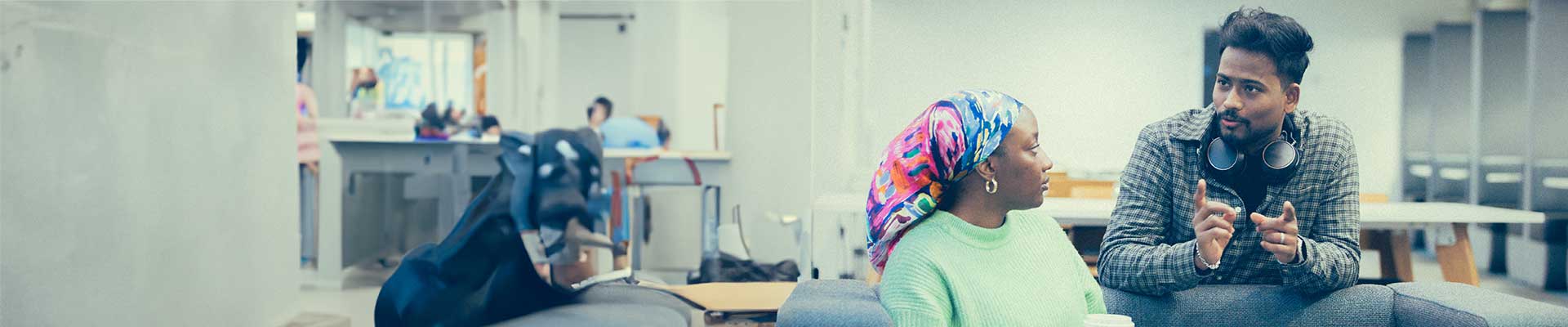 two students chatting over a couch in halls