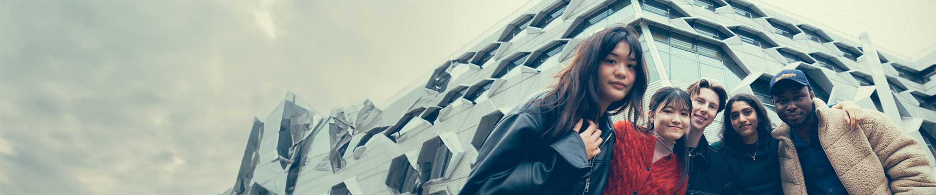 Three students sitting on a stairwell looking at the camera