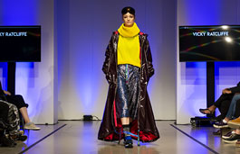 Model walking down catwalk wearing a yellow jumper.