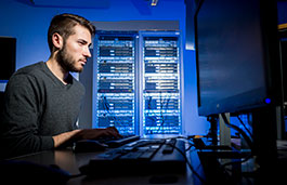 Guy sitting in a server room monitoring the screens