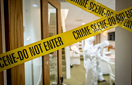 Crime scene tape and forensic officer in room.