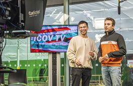 Two male students presenting in a TV studio to a camera in the foreground.
