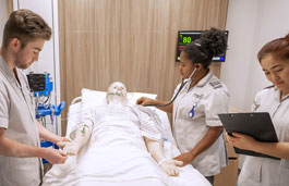 Three nurses examining a model patient