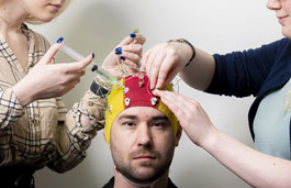 Hands placing a brain activity measuring device on a man's head