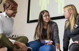 Three students sat on floor in discussion