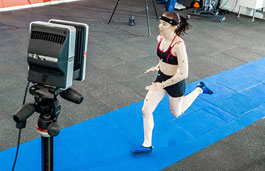 Lady wearing performance measuring devices running on a blue carpet
