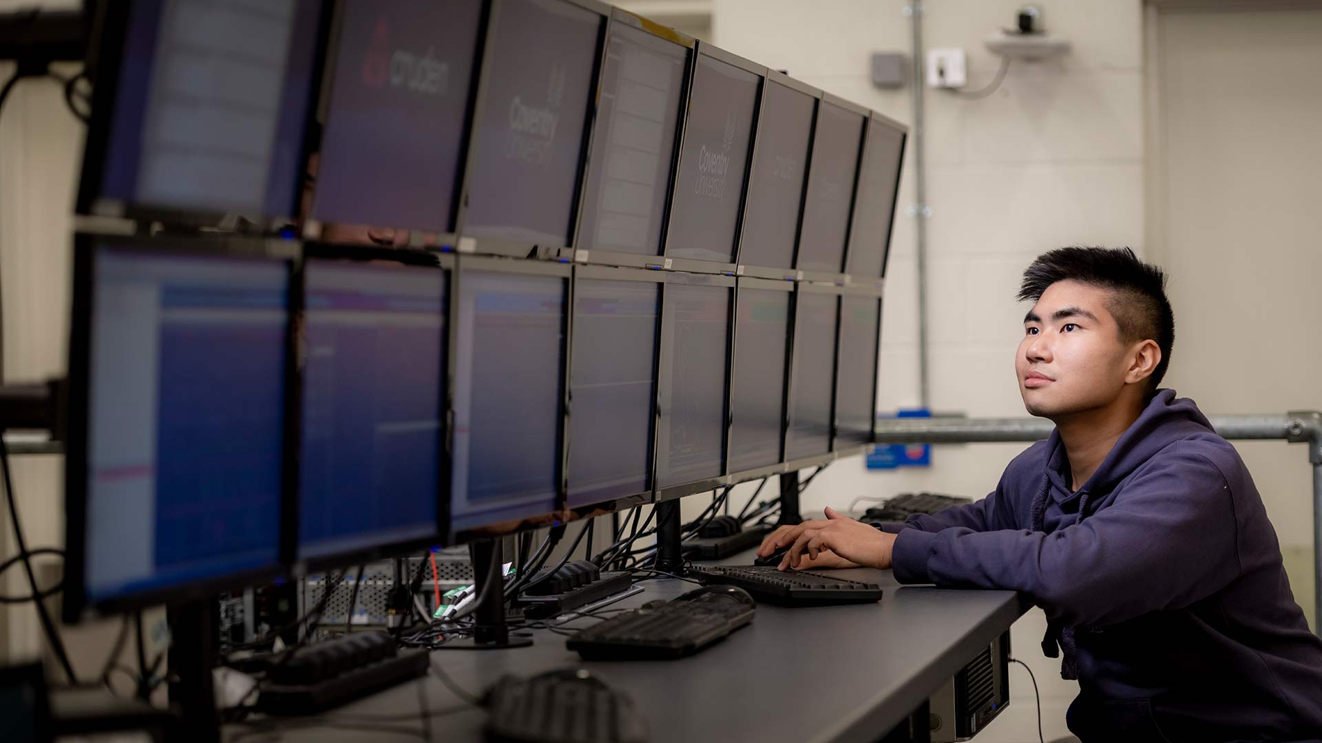 male student looking at a double bank of computer monitors
