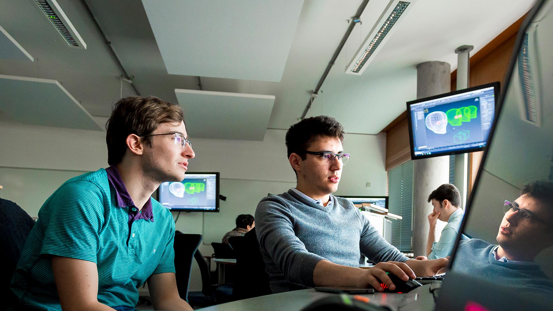 Two students in a classroom working on a laptop screen