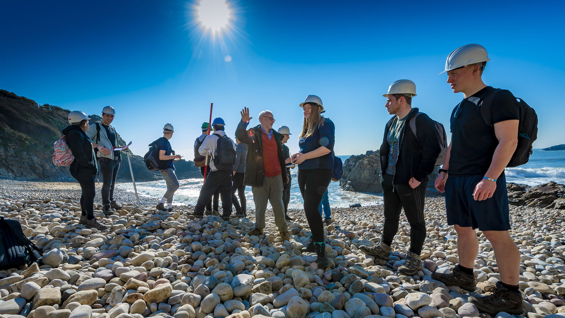 Students on a rocky beach on a sunny day 