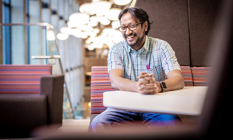 Balaji Aresh leaning on a table smiling