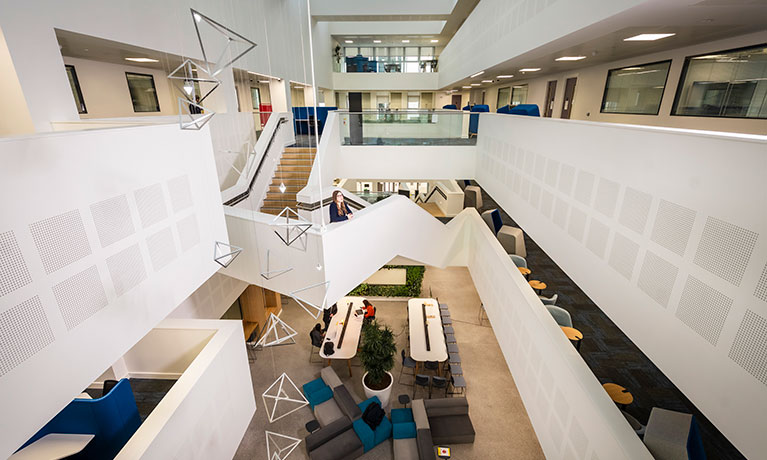 desks for studying within a large building, balconies showing on either side of the area inside the building