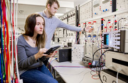 Female and male student using an electronics board