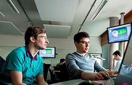 Two students in a classroom working on a laptop screen