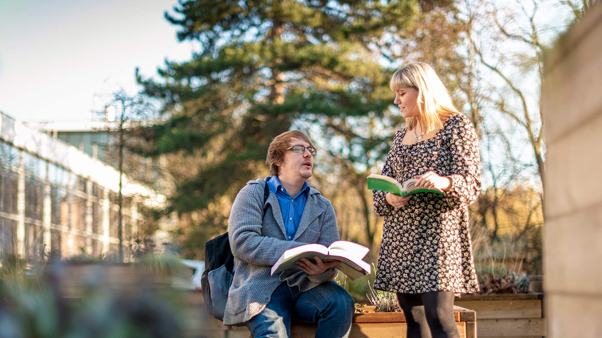 students in uni grounds reading books and chatting 