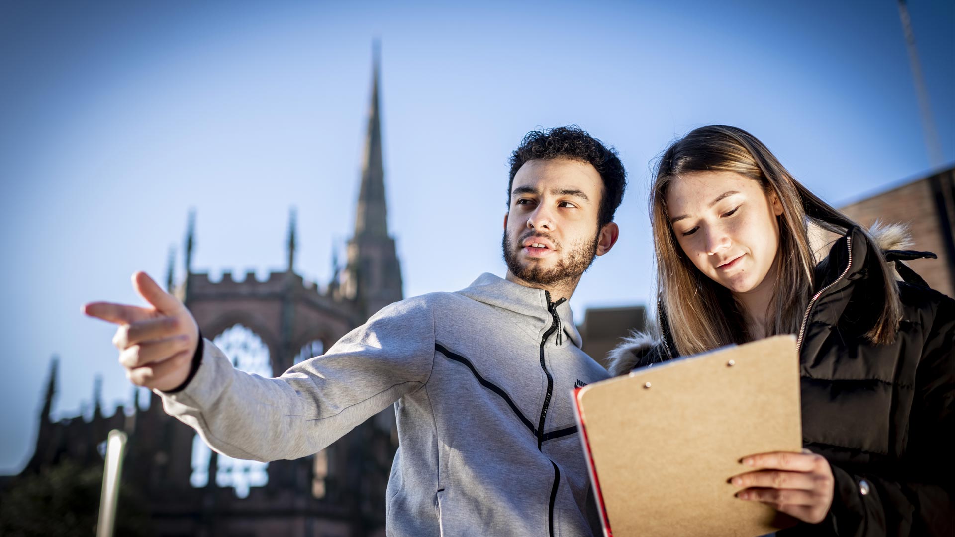 Media student with a clipboard on a shoot in the Coventry Cathedral ruins.