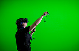 Young woman wearing a VR headset playing against a green screen