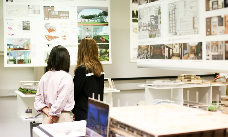 Two students looking at displayed interior design work