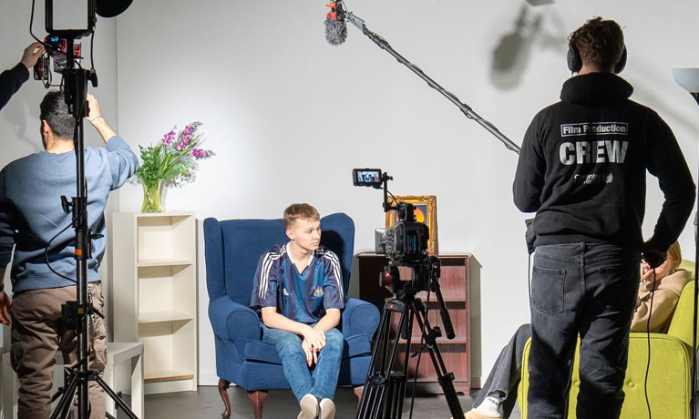 Students recording on a film set, using cameras and sound recording equipment