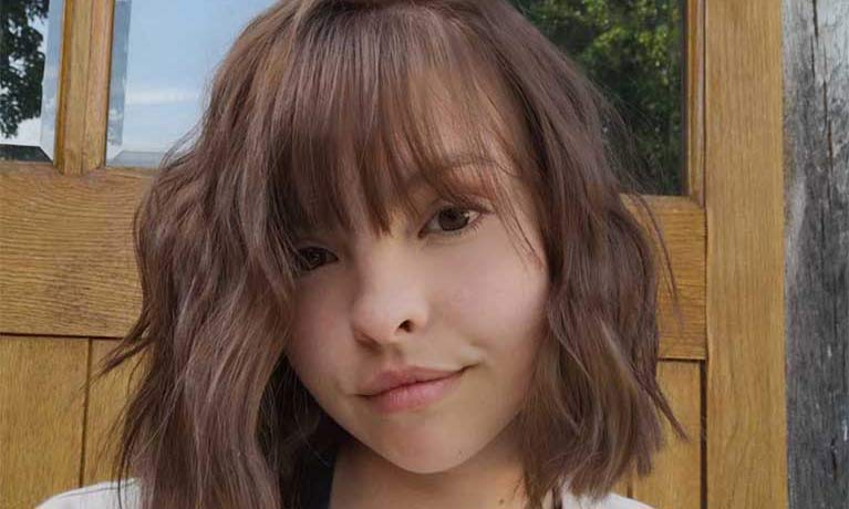 An up-close portrait of a student in front of a wooden door