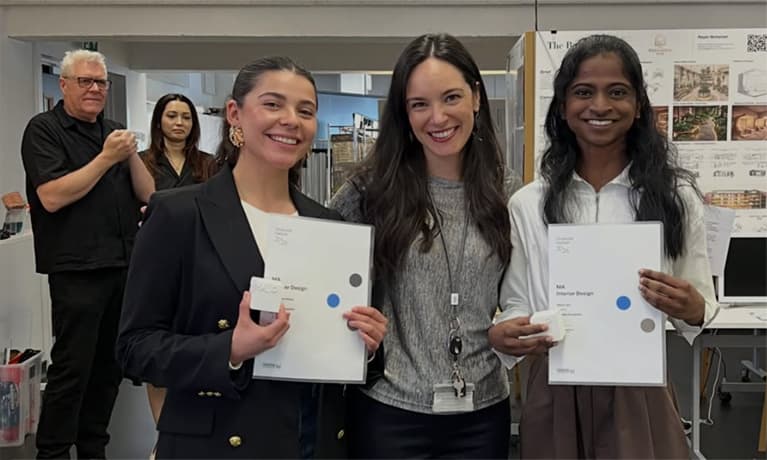 Ana De Areia Soares stood smiling with two of her students smiling with documennts