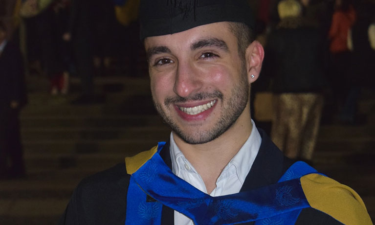 A student smiling, using a Mac computer