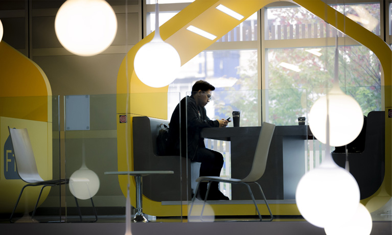 Student sat inside the hub looking at his phone