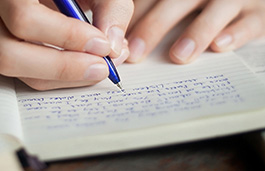 Handwriting on a plain notepad in blue ink