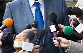Microphones being pointed at a person in a suit