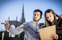 Media student with a clipboard on a shoot in the Coventry Cathedral ruins.