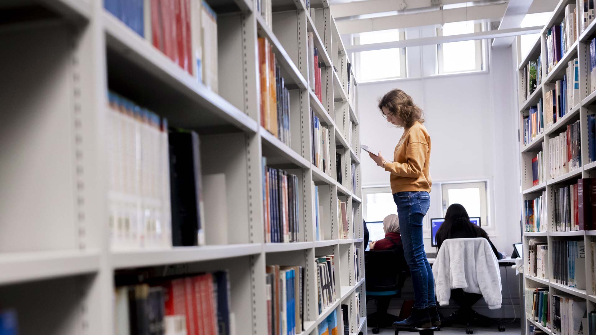 Student looking through the shelves in the library