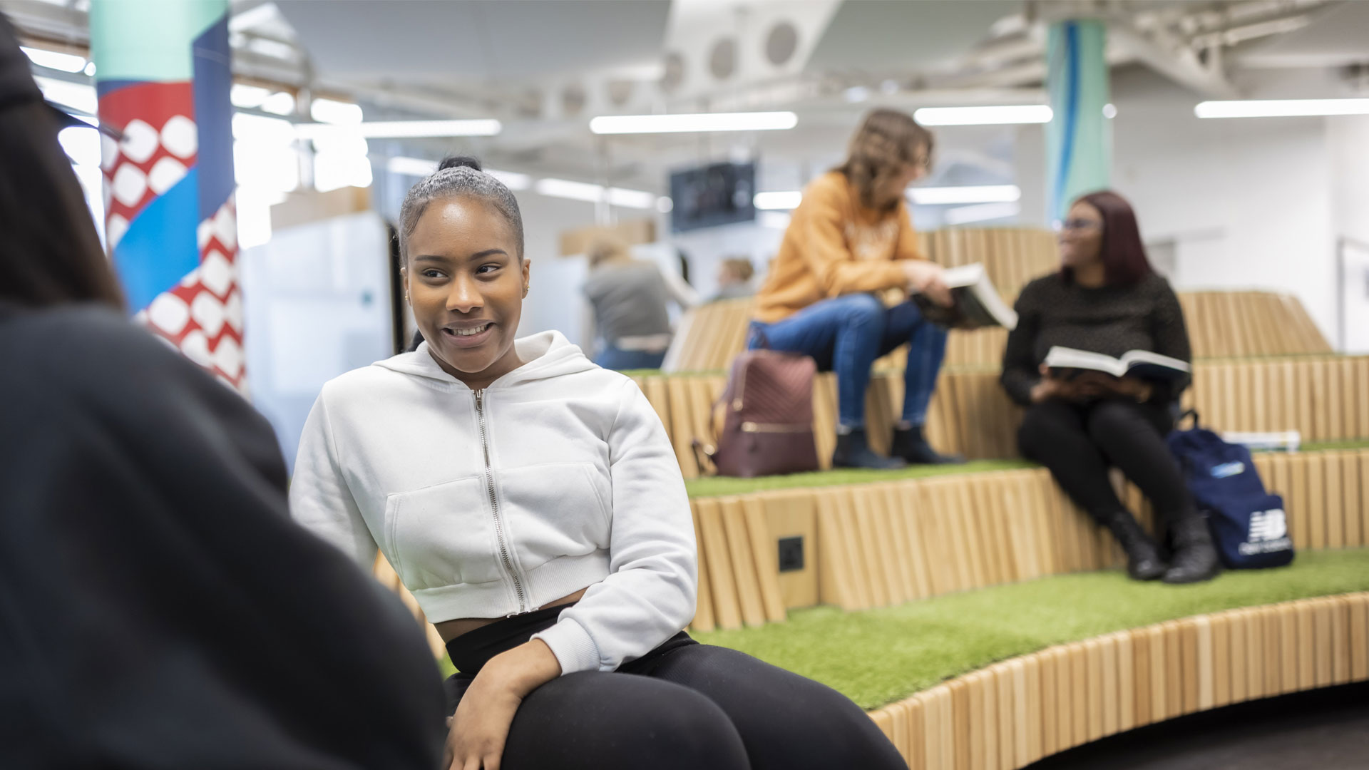 Students talking in an open space with astroturf seating