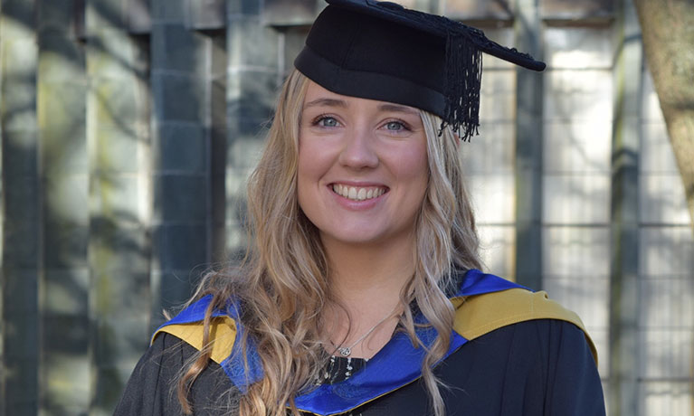Young blonde female wearing a graduation cap and ceremonial clothing