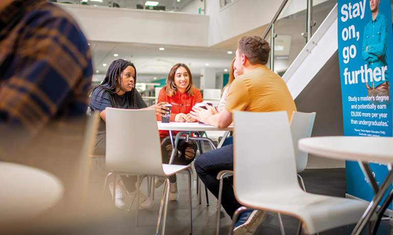 Three students sat around a table talking