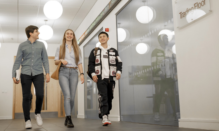 A group of students walking past the Trading Floor