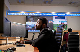 Student sat at desk looking at computer monitors.