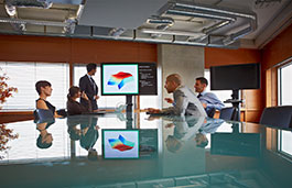 Four people in a conference room looking at a screen