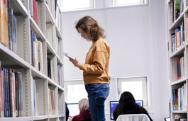 Student looking through the shelves in the library