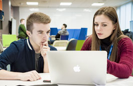 A student and tutor in the DigiComm Lab working on a macbook