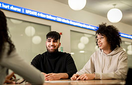 Three students sat at a round desk discussing work