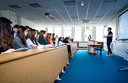students sitting in a classroom with a male lecturer at the front