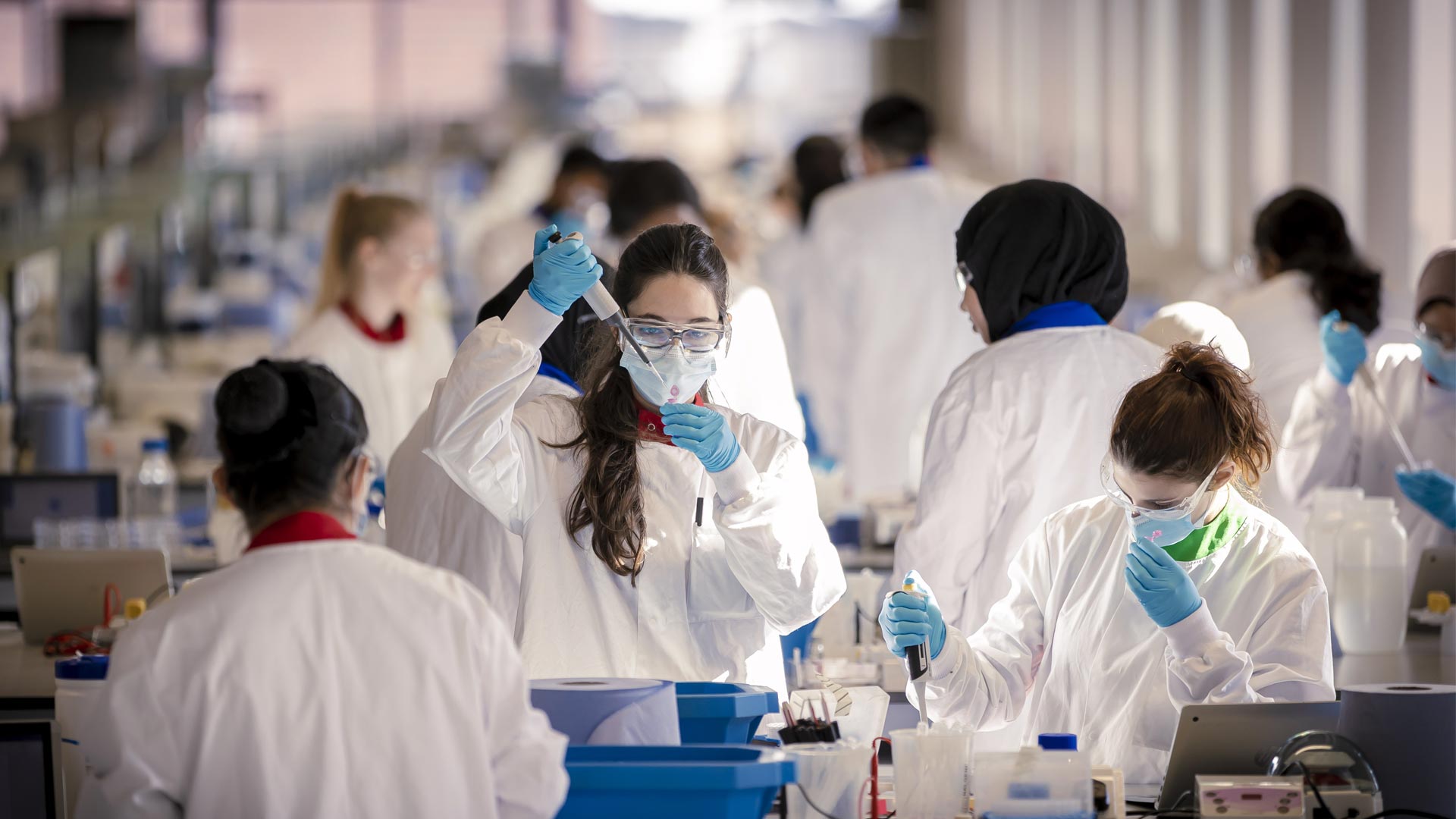 Students wearing white coats and working in the SuperLab.