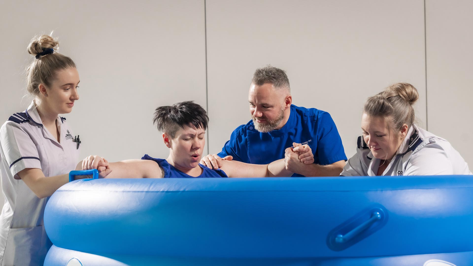 Midwives and students assisting a woman giving bith in a birthng pool.